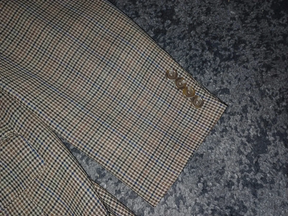 Veste blazer classique en tweed à deux boutons pour homme par Lauren Ralph Lauren, dans un motif micro-pied-de-poule complexe beige, marron et marine. Initialement vendue chez Macy's Men's Store. Marque : Lauren Ralph Lauren Taille : Large (L) Couleur : Micro-carreaux beige, havane, marron et marine Motif : Pied-de-poule / Tweed Guncheck Matière : Extérieur tissé en laine / mélange de laine avec doublure intérieure complète Caractéristiques : Fermeture à deux boutons sur le devant, revers crantés, poignets à quatre boutons, poche poitrine passepoilée, poches à rabat pour les mains, doubles poches intérieures à la poitrine et fente simple au dos État : Excellent état d'occasion, texture tissée nette, doublure complète propre, boutons intacts et les deux étiquettes de marque intérieures entièrement présentes. 5