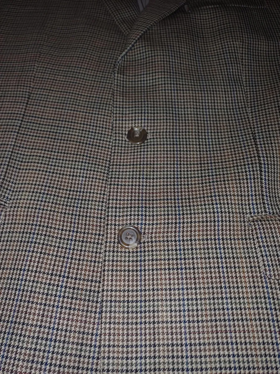 Veste blazer classique en tweed à deux boutons pour homme par Lauren Ralph Lauren, dans un motif micro-pied-de-poule complexe beige, marron et marine. Initialement vendue chez Macy's Men's Store. Marque : Lauren Ralph Lauren Taille : Large (L) Couleur : Micro-carreaux beige, havane, marron et marine Motif : Pied-de-poule / Tweed Guncheck Matière : Extérieur tissé en laine / mélange de laine avec doublure intérieure complète Caractéristiques : Fermeture à deux boutons sur le devant, revers crantés, poignets à quatre boutons, poche poitrine passepoilée, poches à rabat pour les mains, doubles poches intérieures à la poitrine et fente simple au dos État : Excellent état d'occasion, texture tissée nette, doublure complète propre, boutons intacts et les deux étiquettes de marque intérieures entièrement présentes. 4