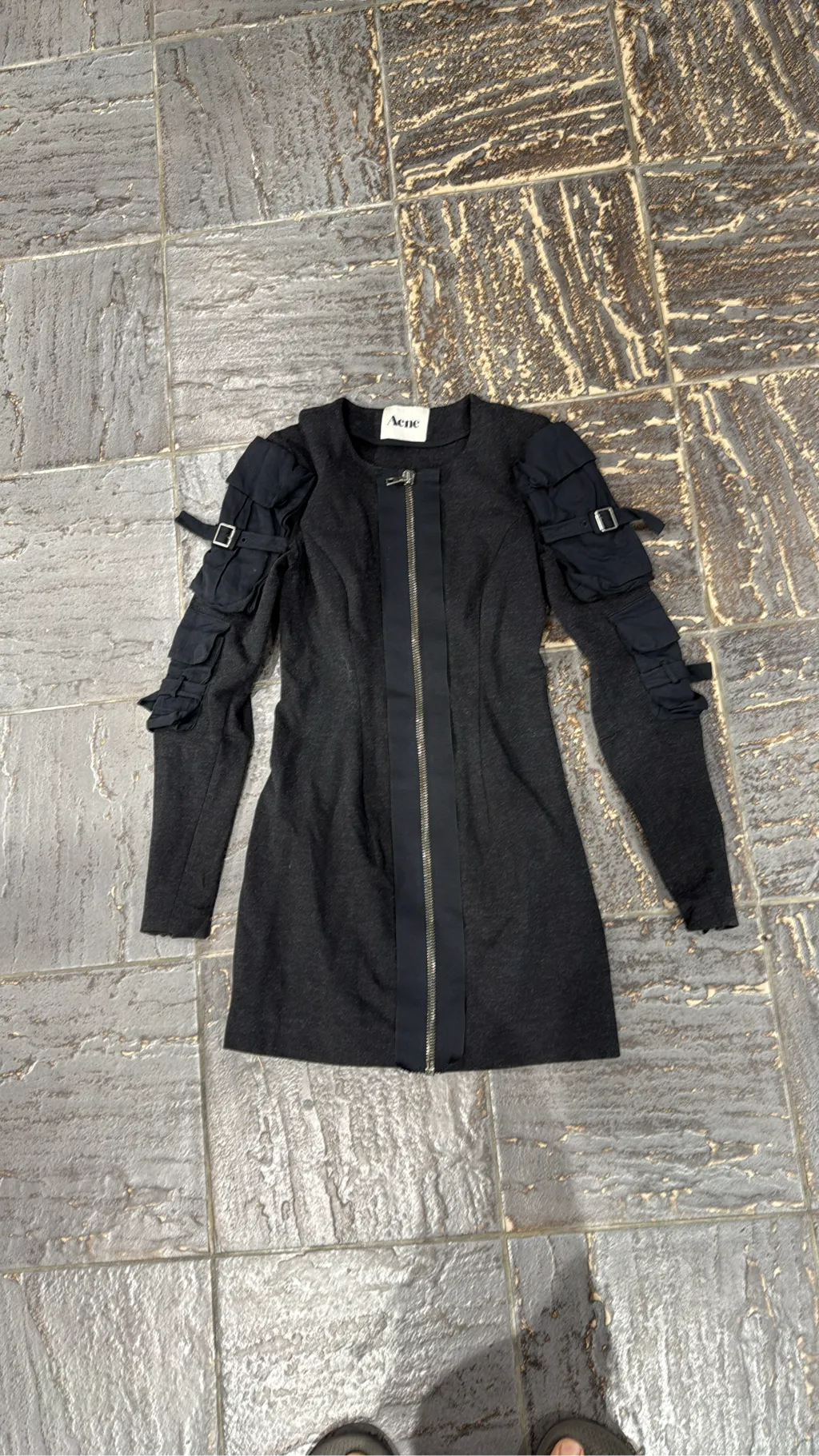 Robe courte grise à manches longues avec des détails de poches cargo et boucles sur les manches, et une fermeture éclair frontale. 1