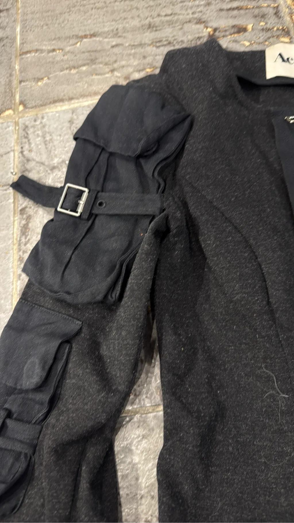 Robe courte grise à manches longues avec des détails de poches cargo et boucles sur les manches, et une fermeture éclair frontale. 2