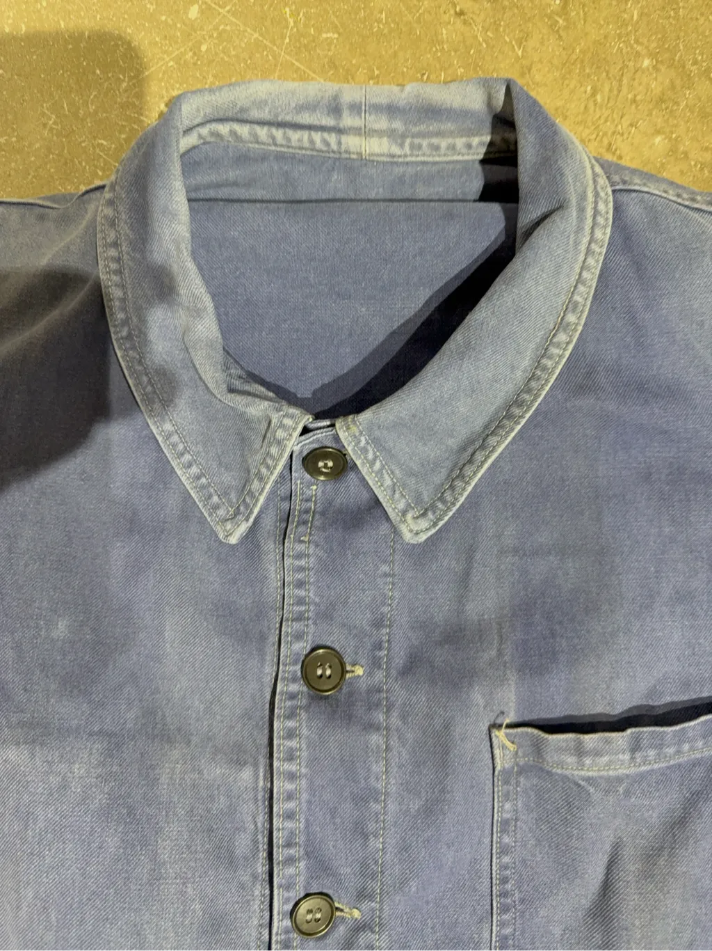Veste de travail vintage bleue en coton, avec des poches plaquées, une usure authentique et un patch de réparation visible sur une poche. 3