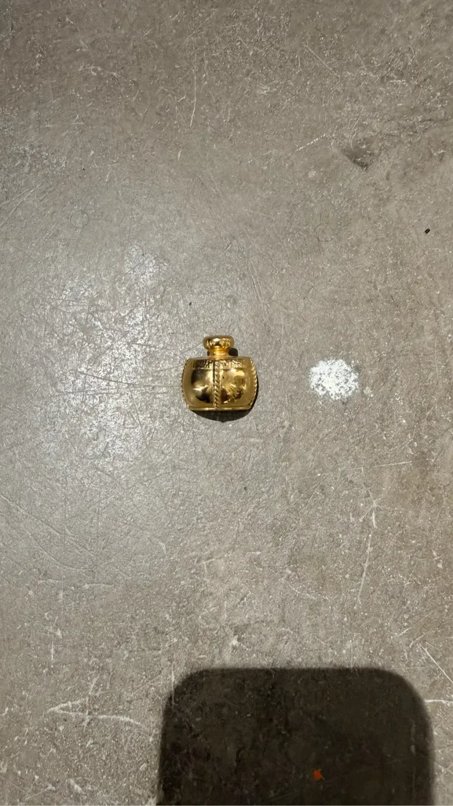 Small brooch shaped like a gilded ornate miniature bottle. YSL 1