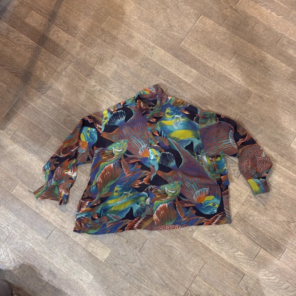 Chemise à manches longues imprimée de motifs de poissons multicolores sur fond noir.