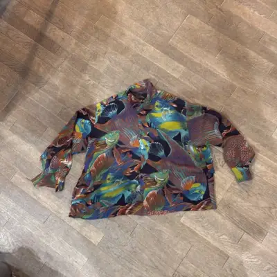 Chemise à manches longues imprimée de motifs de poissons multicolores sur fond noir.
