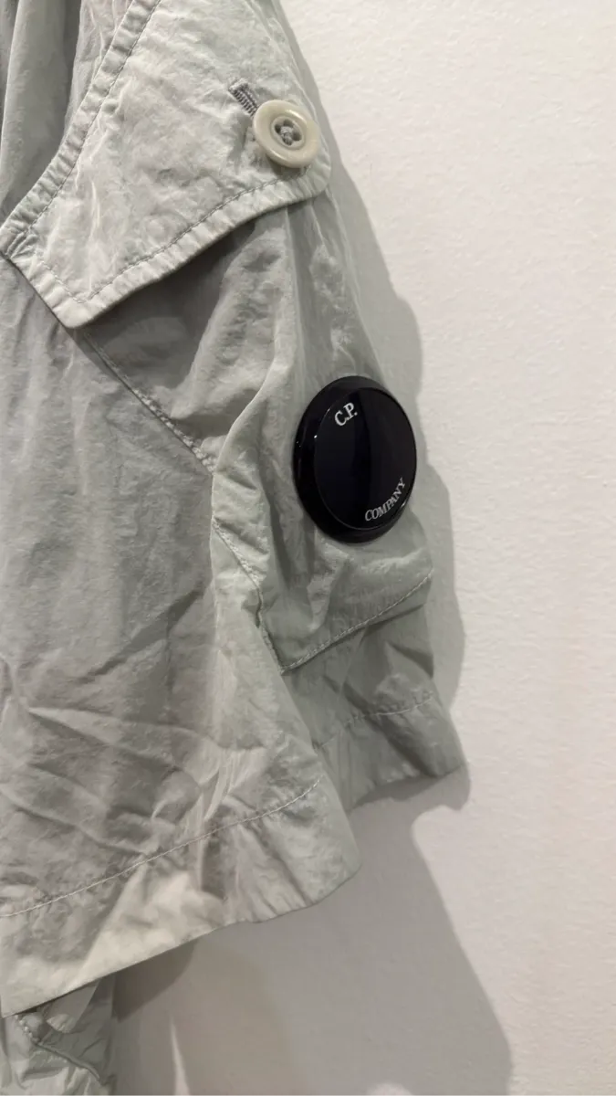 Chemise-veste à manches courtes C.P. Company en nylon recyclé Chrome-R, de couleur gris clair, avec un patch logo sur la manche. 3