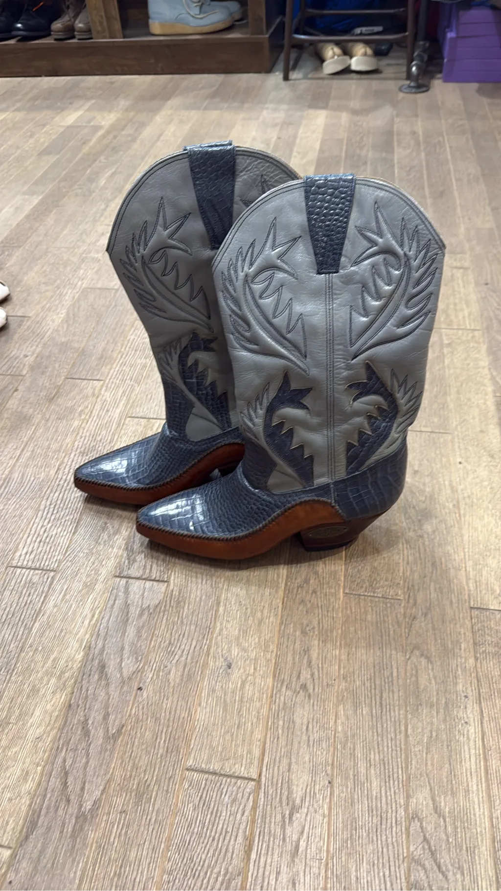 Bottes de cowboy bicolores en cuir gris et bleu avec texture crocodile et broderies décoratives, dotées d'un talon en bois et d'une plaque Rango Texas.