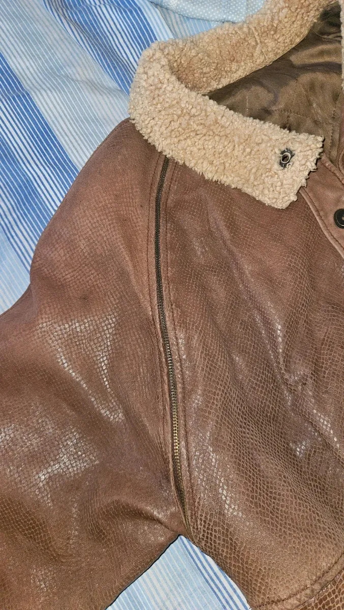 Cette veste VFORTI est confectionnée en cuir marron souple à motif serpenté. Les manches sont amovibles. Très bon état, avec quelques signes d'usure dus au temps. 5