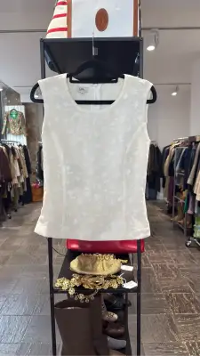 Top sans manches écru avec motif floral texturé et fermeture éclair au dos.