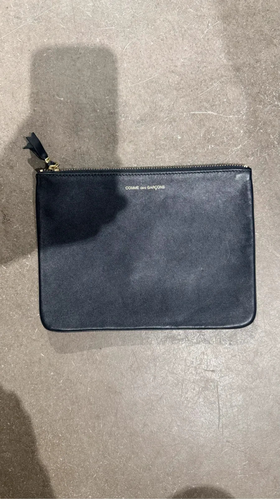 Comme des Garçons black leather clutch with gold logo and zip. Dimensions 21 x 15.5 cm