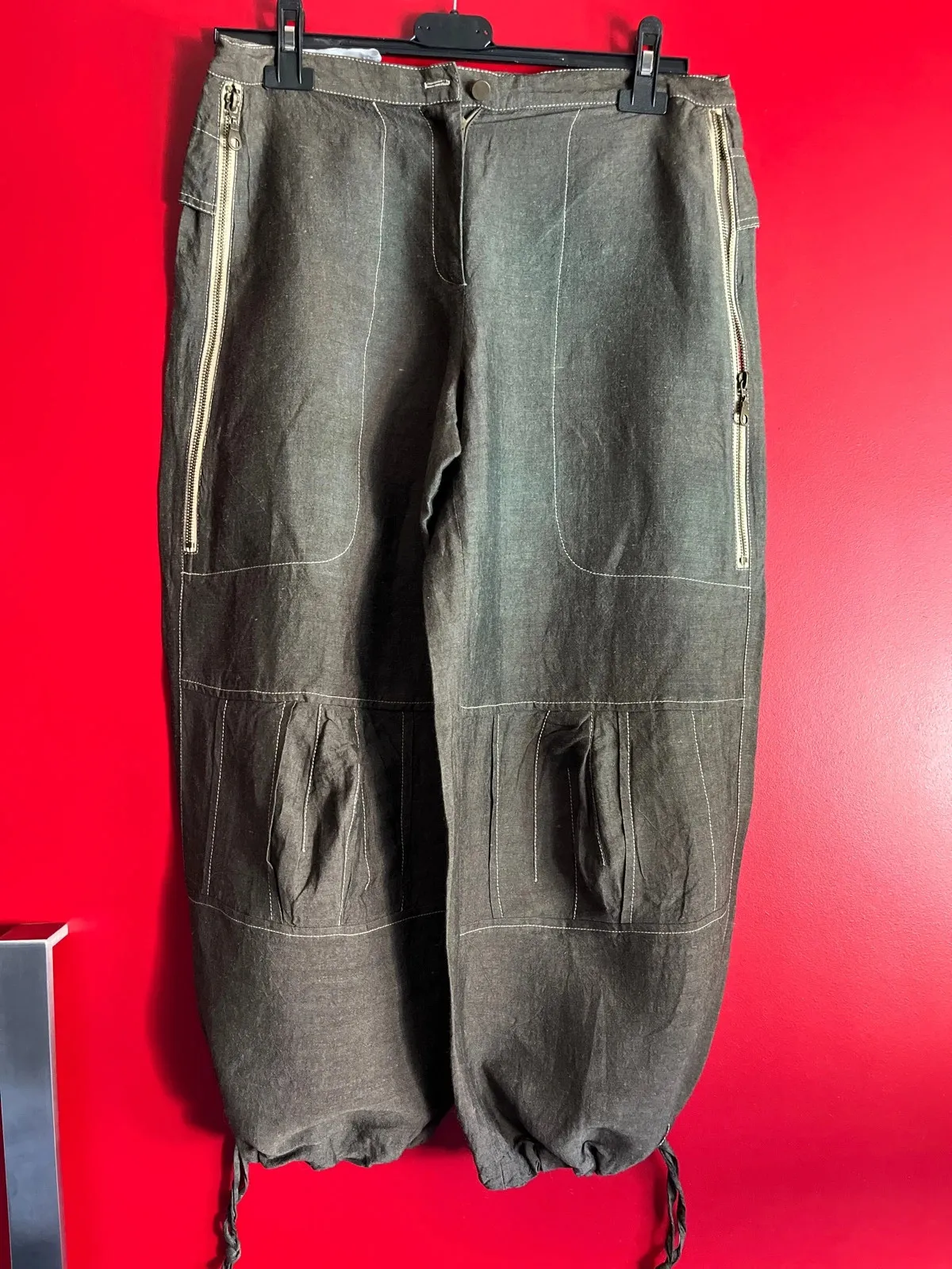 Très beau pantalon original, hauteur chevilles. Deux grandes poches zippées devant avec motifs fleuris à l'intérieur. Quelques pinces aux niveaux des genoux. Deux fausses poches à l'arrière avec motifs floraux à l'intérieur du rabat. Lien de serrage au bas des jambes. Taille à plat 40 cms, longueur ceinture à l'entrejambe 31 cms, longueur totale du pantalon 84 cms. Couleur chocolat au lait. 11