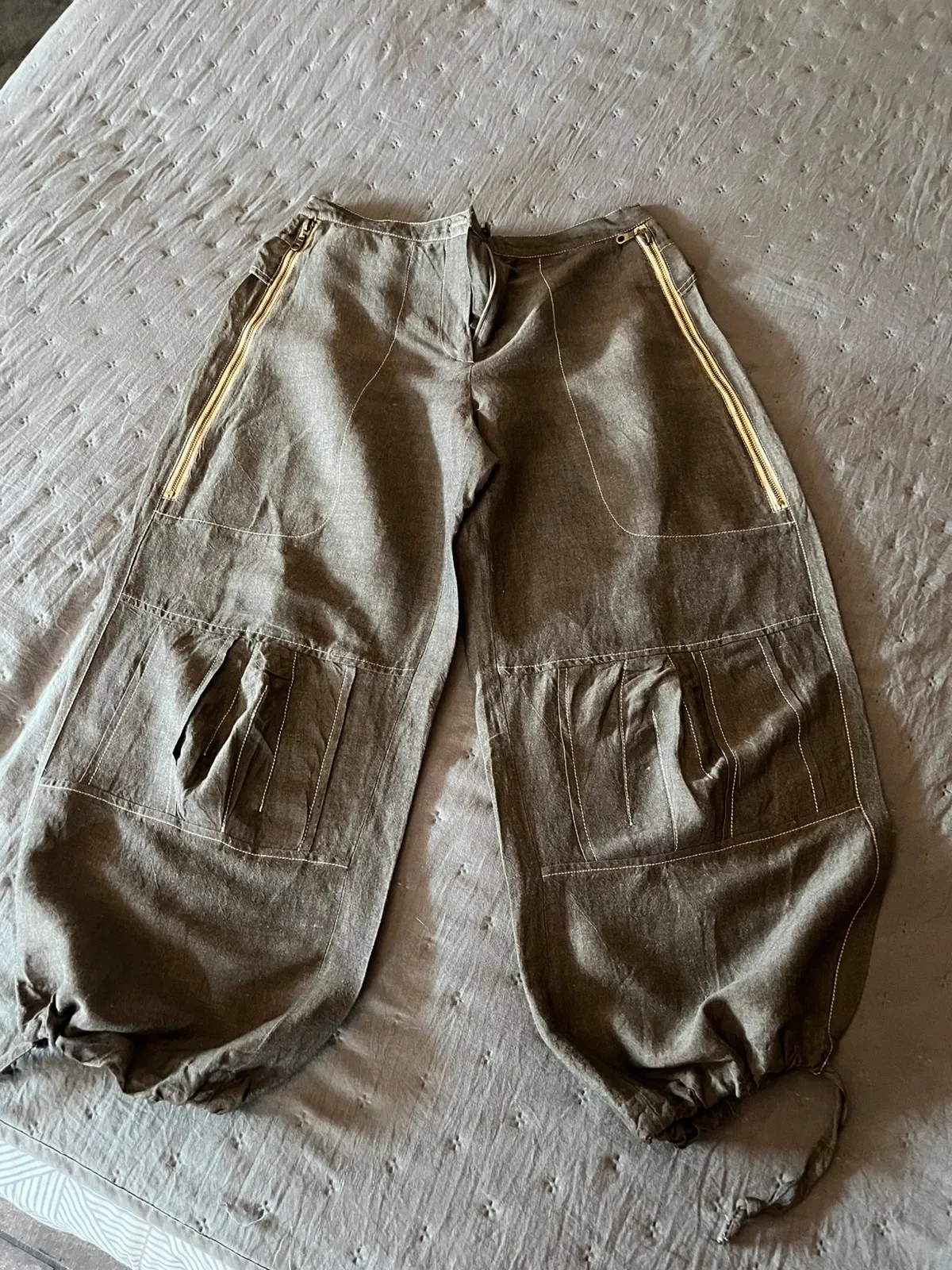 Très beau pantalon original, hauteur chevilles. Deux grandes poches zippées devant avec motifs fleuris à l'intérieur. Quelques pinces aux niveaux des genoux. Deux fausses poches à l'arrière avec motifs floraux à l'intérieur du rabat. Lien de serrage au bas des jambes. Taille à plat 40 cms, longueur ceinture à l'entrejambe 31 cms, longueur totale du pantalon 84 cms. Couleur chocolat au lait. 1