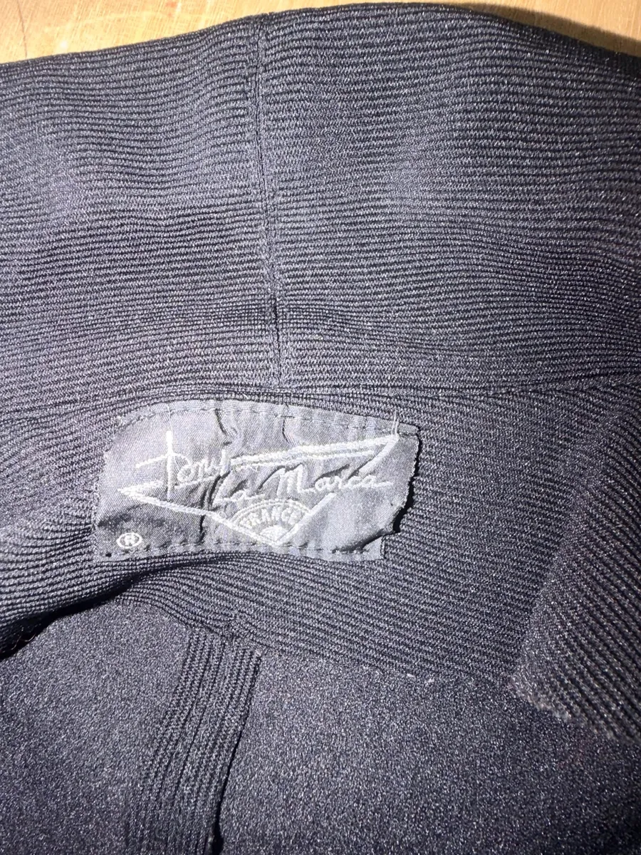 ✨ Une pièce vintage d'exception au style couture et affirmé ! Superbe veste de tailleur / blazer vintage noir de la marque créateur Tony La Marca France, coupe travaillée et très élégante. ✨ Détails & Coupe : Col châle croisé à l'avant, fermeture par bouton, détails de petits boutons décoratifs structurant le côté de la taille. Tissu côtelé / strié de très belle tenue. 📐 Dimensions & Taille : Largeur aisselle à aisselle : 47 cm (convient à un 38 - M). 🧵 Qualité : Belle confection française vintage, pièce originale et structurée. 9