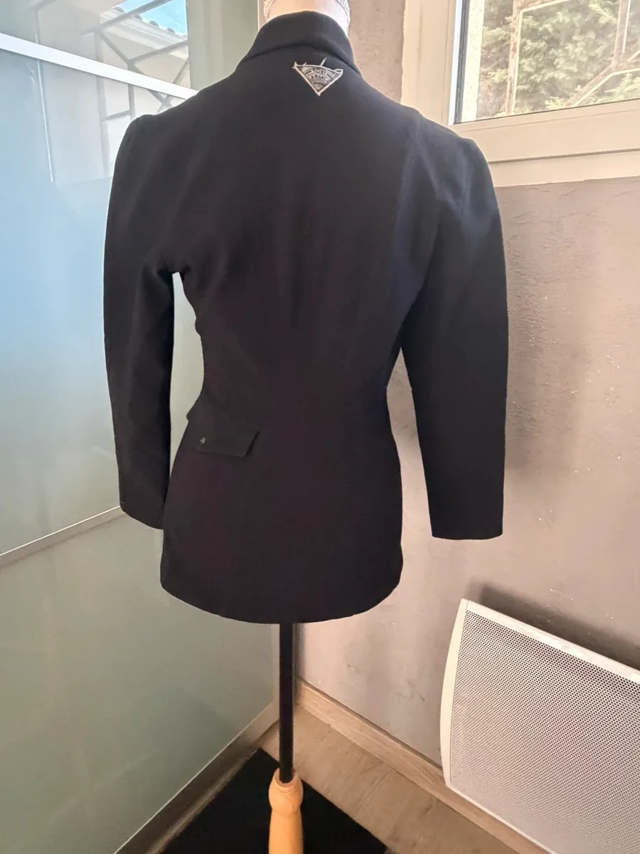 ✨ Une pièce vintage d'exception au style couture et affirmé ! Superbe veste de tailleur / blazer vintage noir de la marque créateur Tony La Marca France, coupe travaillée et très élégante. ✨ Détails & Coupe : Col châle croisé à l'avant, fermeture par bouton, détails de petits boutons décoratifs structurant le côté de la taille. Tissu côtelé / strié de très belle tenue. 📐 Dimensions & Taille : Largeur aisselle à aisselle : 47 cm (convient à un 38 - M). 🧵 Qualité : Belle confection française vintage, pièce originale et structurée. 3