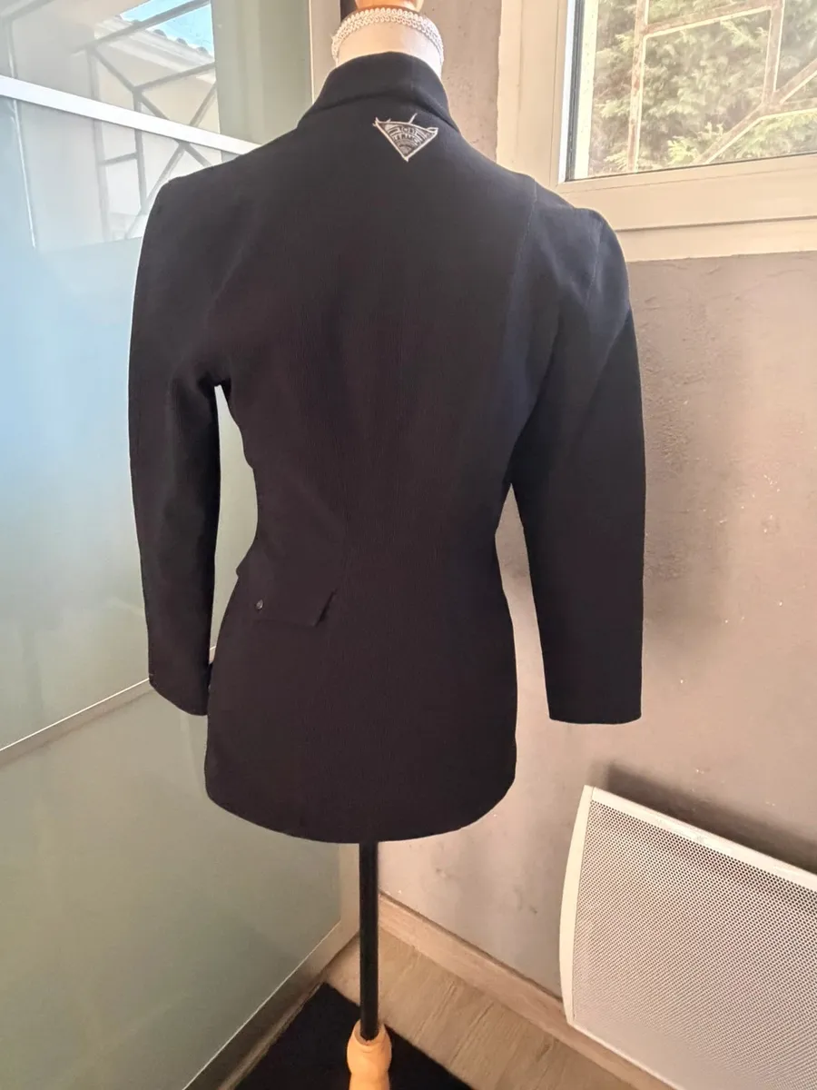 ✨ Une pièce vintage d'exception au style couture et affirmé ! Superbe veste de tailleur / blazer vintage noir de la marque créateur Tony La Marca France, coupe travaillée et très élégante. ✨ Détails & Coupe : Col châle croisé à l'avant, fermeture par bouton, détails de petits boutons décoratifs structurant le côté de la taille. Tissu côtelé / strié de très belle tenue. 📐 Dimensions & Taille : Largeur aisselle à aisselle : 47 cm (convient à un 38 - M). 🧵 Qualité : Belle confection française vintage, pièce originale et structurée. 5