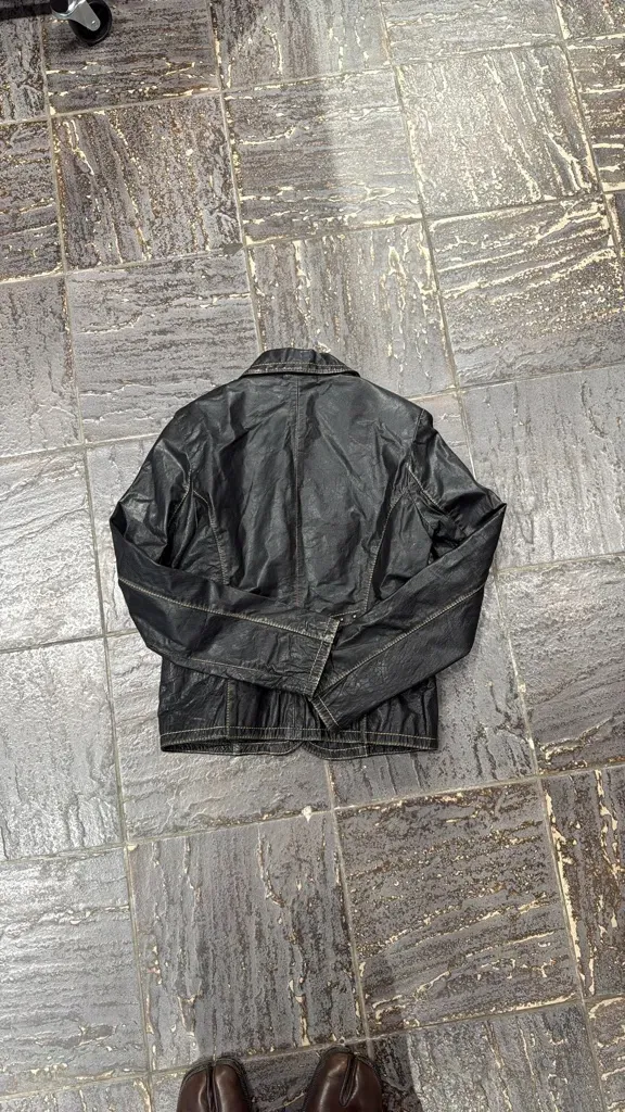 Black leather jacket with decorative silver buttons and contrasting topstitching, featuring two front flap pockets. 6
