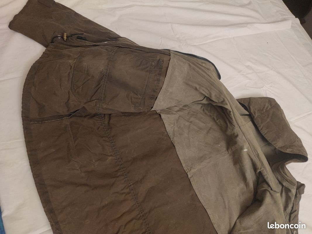 Blouson ou veste courte huilé de la marque FILSON A Genuine C.C. FILSON CO. SEATTLE.
Avec deux poches à l'extérieur et deux poches protège mains, une poche à l'intérieur.
Le bout des manches est tricoté et doublé. Capuche avec lacet de serrage. En parfait état.
C'est une taille L. 8