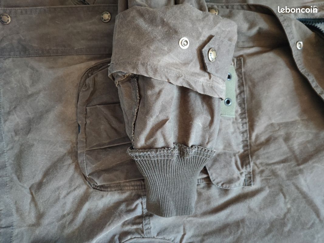 Blouson ou veste courte huilé de la marque FILSON A Genuine C.C. FILSON CO. SEATTLE.
Avec deux poches à l'extérieur et deux poches protège mains, une poche à l'intérieur.
Le bout des manches est tricoté et doublé. Capuche avec lacet de serrage. En parfait état.
C'est une taille L. 11