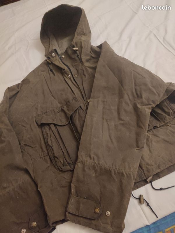 Blouson ou veste courte huilé de la marque FILSON A Genuine C.C. FILSON CO. SEATTLE.
Avec deux poches à l'extérieur et deux poches protège mains, une poche à l'intérieur.
Le bout des manches est tricoté et doublé. Capuche avec lacet de serrage. En parfait état.
C'est une taille L. 4