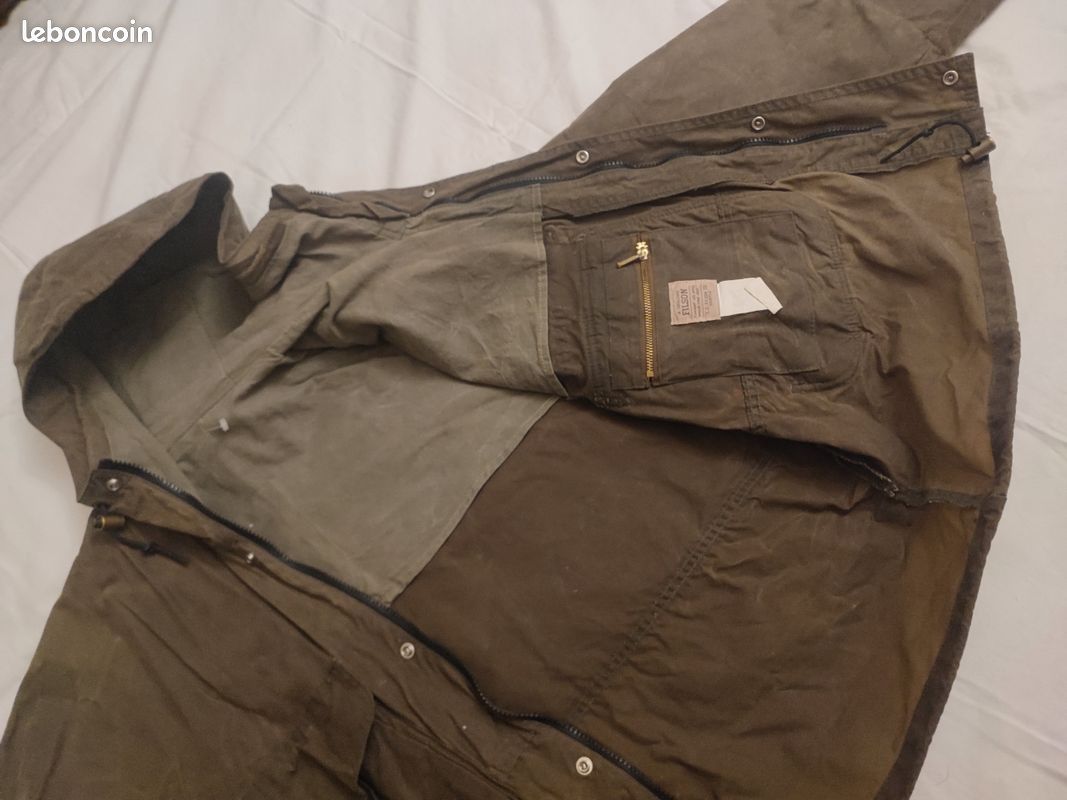 Blouson ou veste courte huilé de la marque FILSON A Genuine C.C. FILSON CO. SEATTLE.
Avec deux poches à l'extérieur et deux poches protège mains, une poche à l'intérieur.
Le bout des manches est tricoté et doublé. Capuche avec lacet de serrage. En parfait état.
C'est une taille L. 7