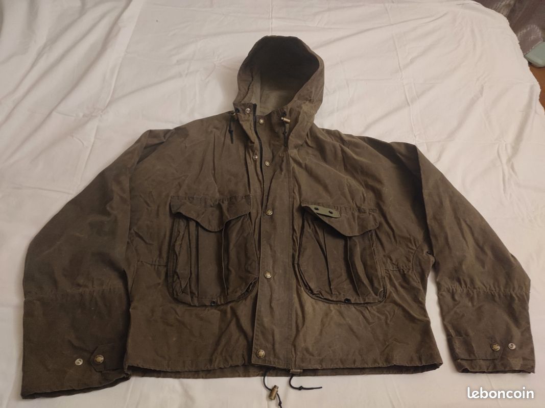 Blouson ou veste courte huilé de la marque FILSON A Genuine C.C. FILSON CO. SEATTLE.
Avec deux poches à l'extérieur et deux poches protège mains, une poche à l'intérieur.
Le bout des manches est tricoté et doublé. Capuche avec lacet de serrage. En parfait état.
C'est une taille L. 1