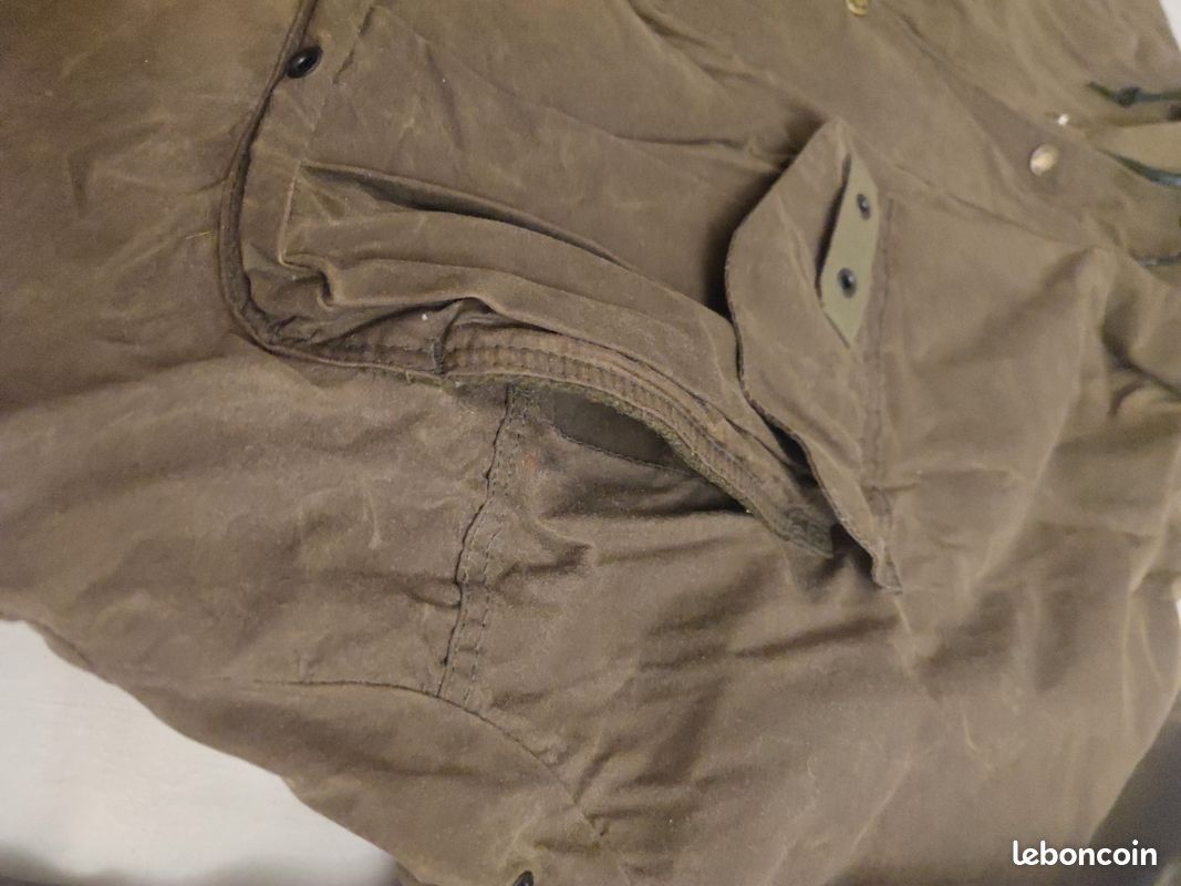 Blouson ou veste courte huilé de la marque FILSON A Genuine C.C. FILSON CO. SEATTLE.
Avec deux poches à l'extérieur et deux poches protège mains, une poche à l'intérieur.
Le bout des manches est tricoté et doublé. Capuche avec lacet de serrage. En parfait état.
C'est une taille L. 10