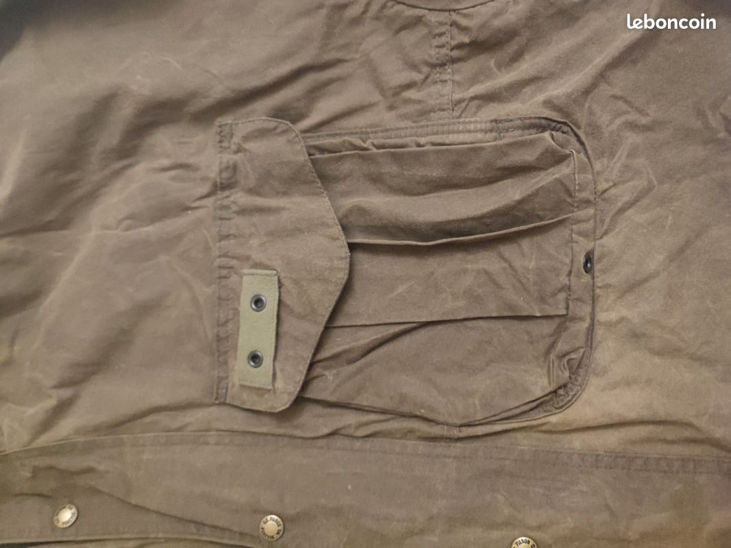 Blouson ou veste courte huilé de la marque FILSON A Genuine C.C. FILSON CO. SEATTLE.
Avec deux poches à l'extérieur et deux poches protège mains, une poche à l'intérieur.
Le bout des manches est tricoté et doublé. Capuche avec lacet de serrage. En parfait état.
C'est une taille L. 6