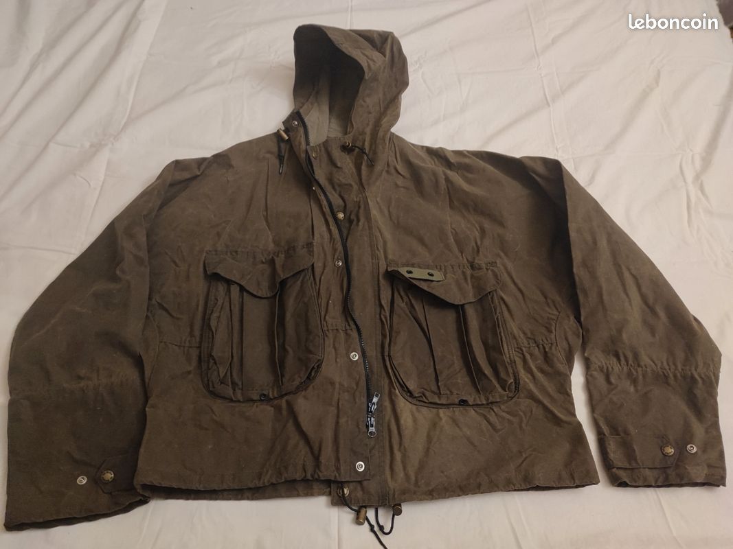 Blouson ou veste courte huilé de la marque FILSON A Genuine C.C. FILSON CO. SEATTLE.
Avec deux poches à l'extérieur et deux poches protège mains, une poche à l'intérieur.
Le bout des manches est tricoté et doublé. Capuche avec lacet de serrage. En parfait état.
C'est une taille L. 2