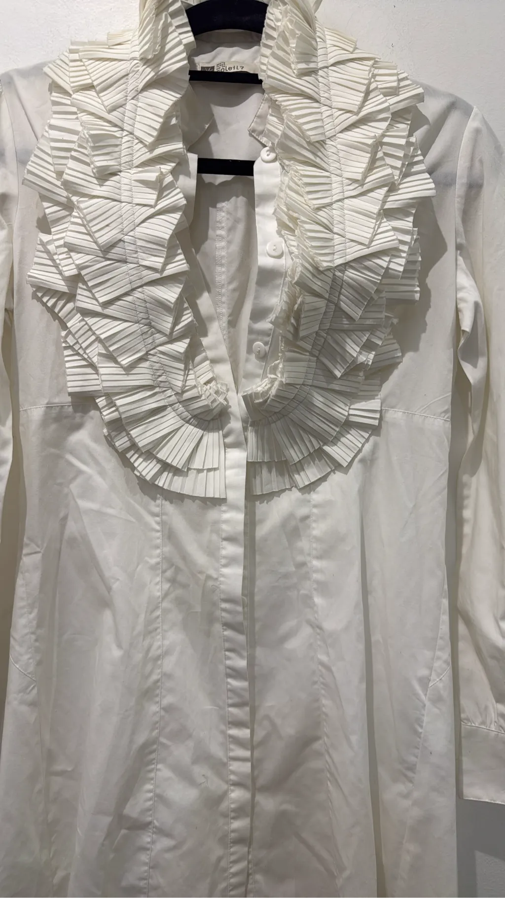 Blouse blanche à manches longues avec un grand col et des volants plissés sur le devant. 3