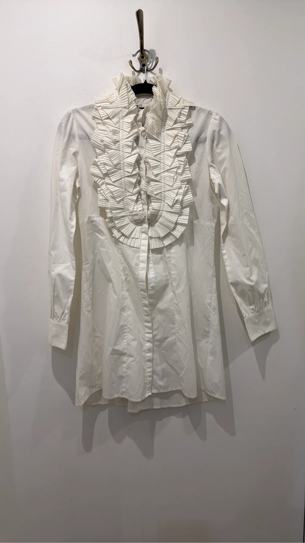 Blouse blanche à manches longues avec un grand col et des volants plissés sur le devant. 4