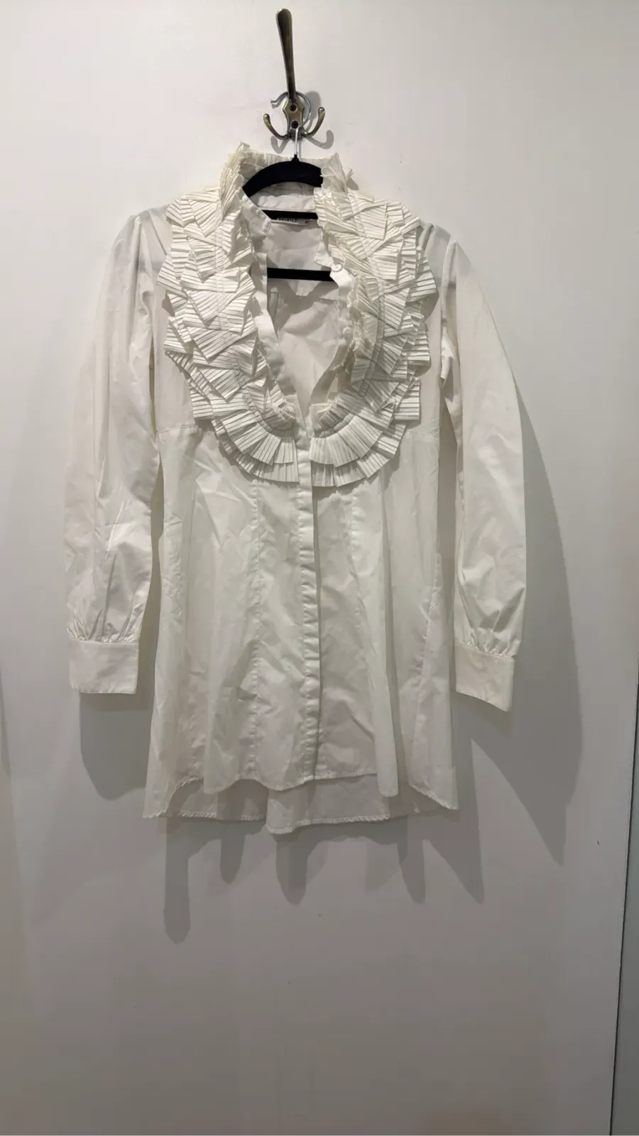 White long-sleeve blouse with a large collar and pleated ruffles on the front.