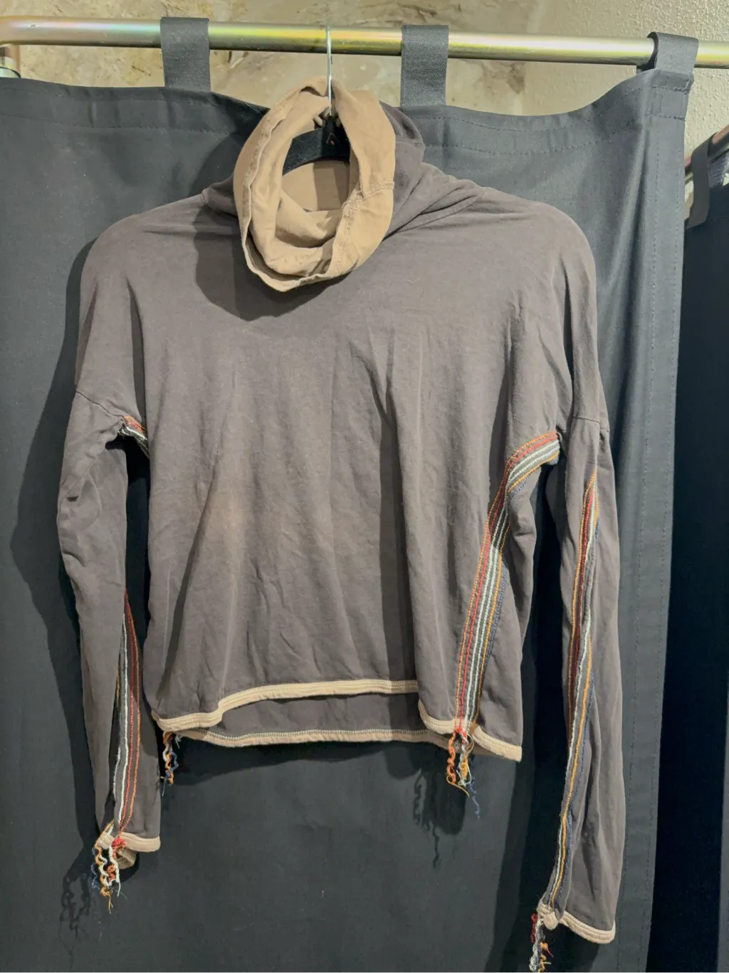 Haut à manches longues en coton anthracite avec col bénitier beige, coutures apparentes multicolores et bords effilochés.
