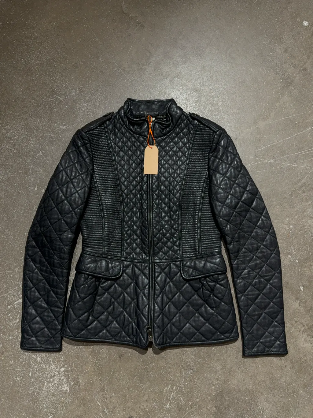 Veste matelassée en cuir noir pour femme avec fermeture éclair et détails côtelés.