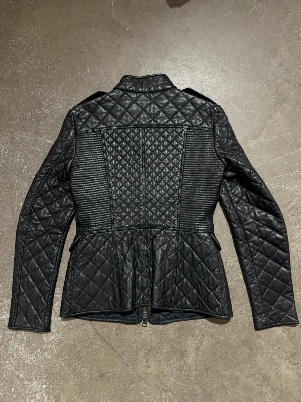Veste matelassée en cuir noir pour femme avec fermeture éclair et détails côtelés. 2