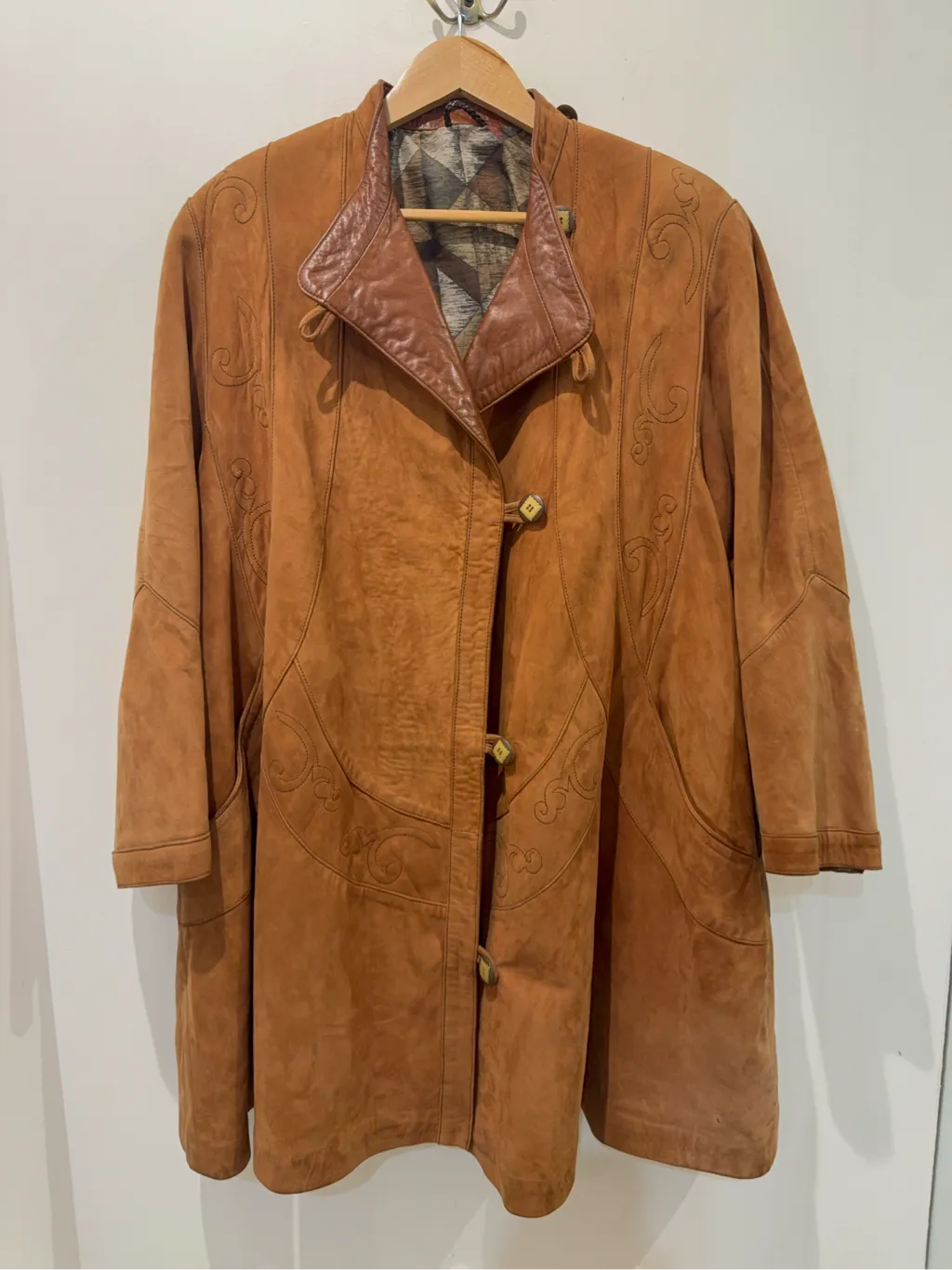 Manteau long en daim camel avec col en cuir marron et broderies décoratives.