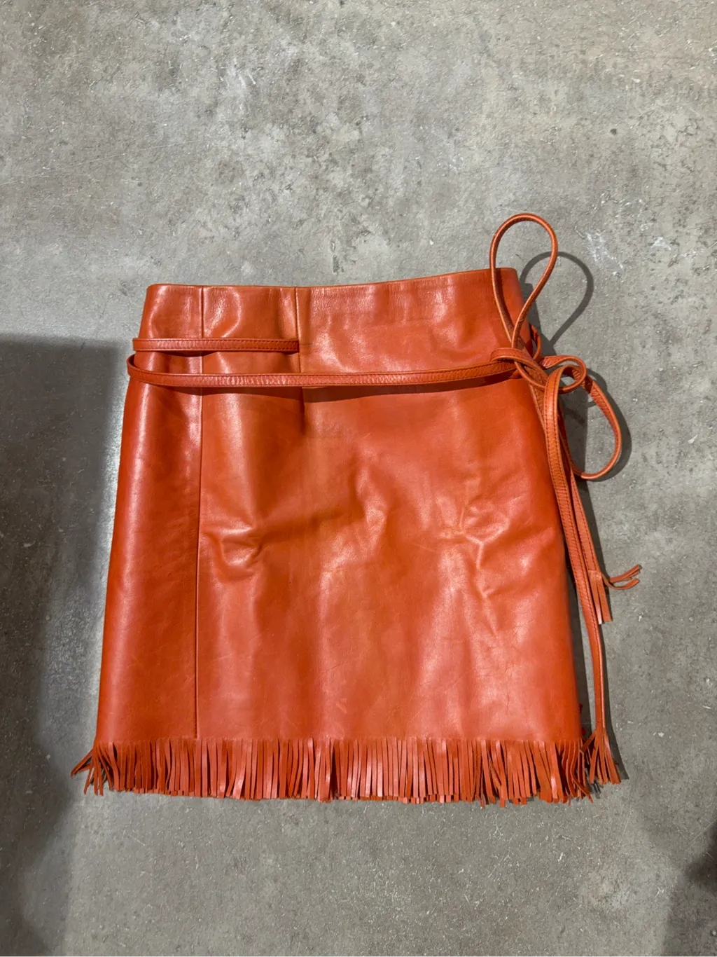 Mini-jupe portefeuille en cuir orange avec franges à l'ourlet. 2