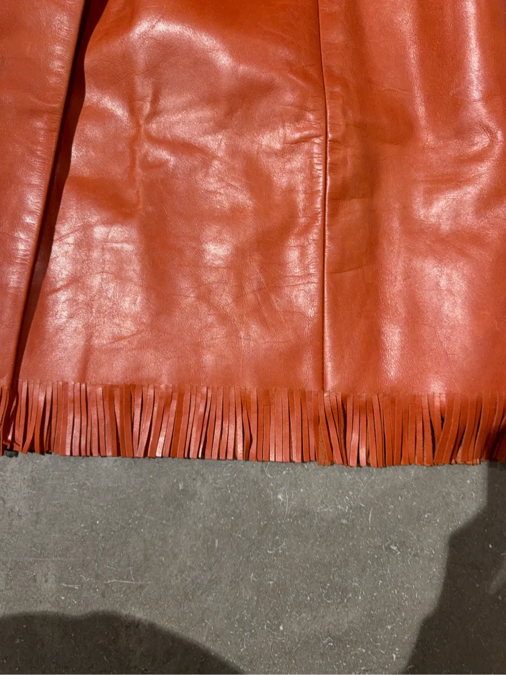 Mini-jupe portefeuille en cuir orange avec franges à l'ourlet. 3