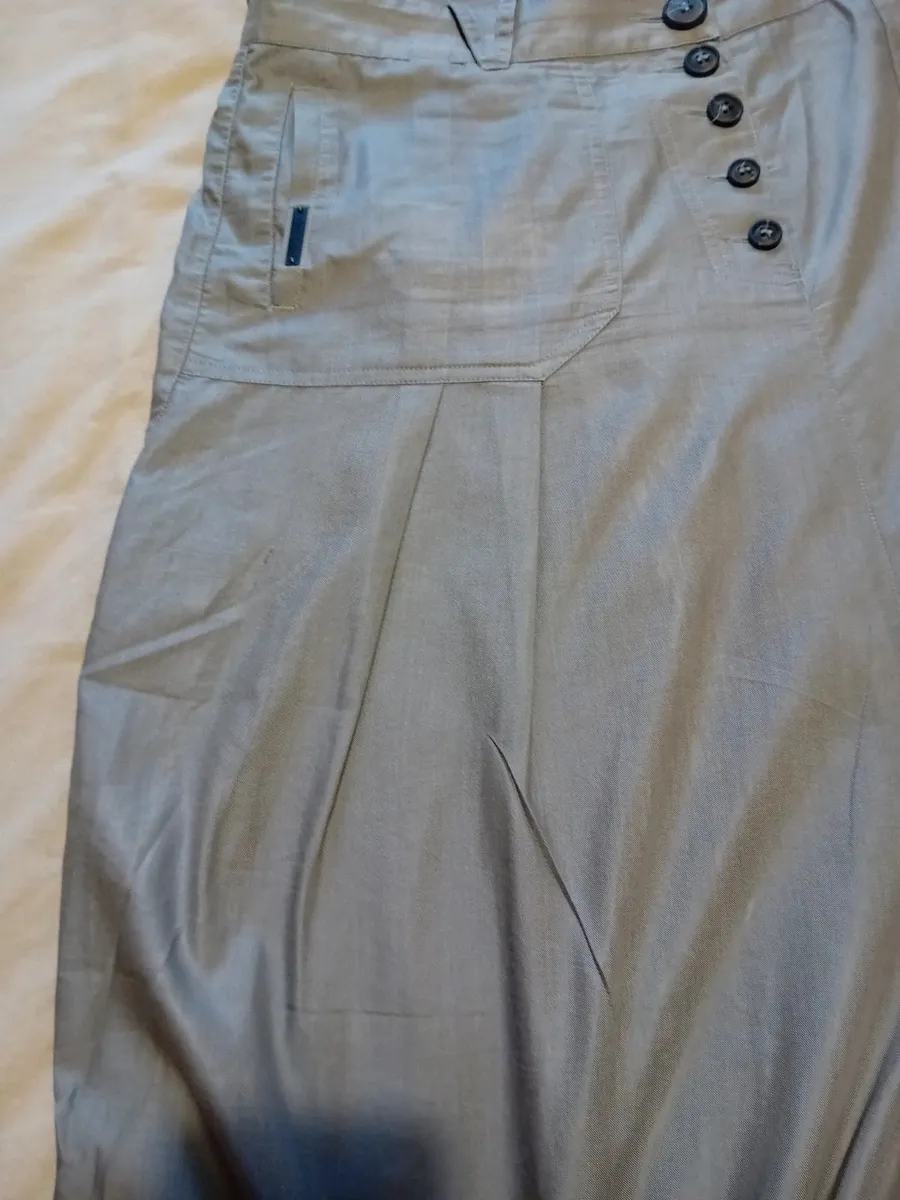 Jupe sarouel avec fronces en bas de chaque jambe, fronces plates sur le devant
2 poches arrières
Boutonnières devant
Taille 42 de chez cop copine
Très bon état tissu souple et fin ,gris clair 3
