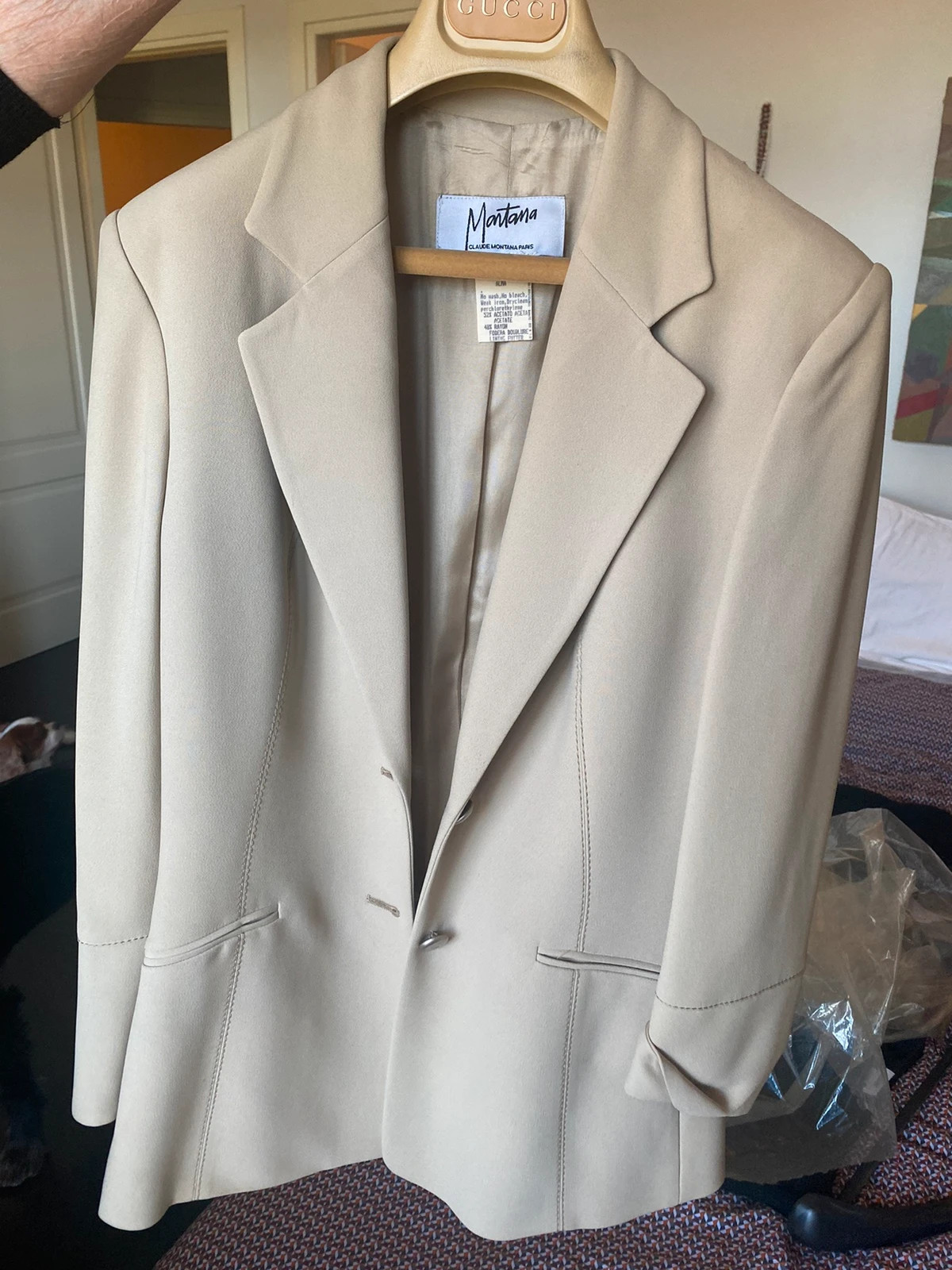 Veste de tailleur Claude Montana, créateur français emblématique des années 1980-90. Coloris beige uni, coupe structurée à épaules marquées — signature Montana —, revers cranté et boutonnage simple. Entièrement doublée. Taille 36-38 (étiquette L). Excellent état vintage. Une pièce de créateur graphique et intemporelle pour structurer la silhouette.