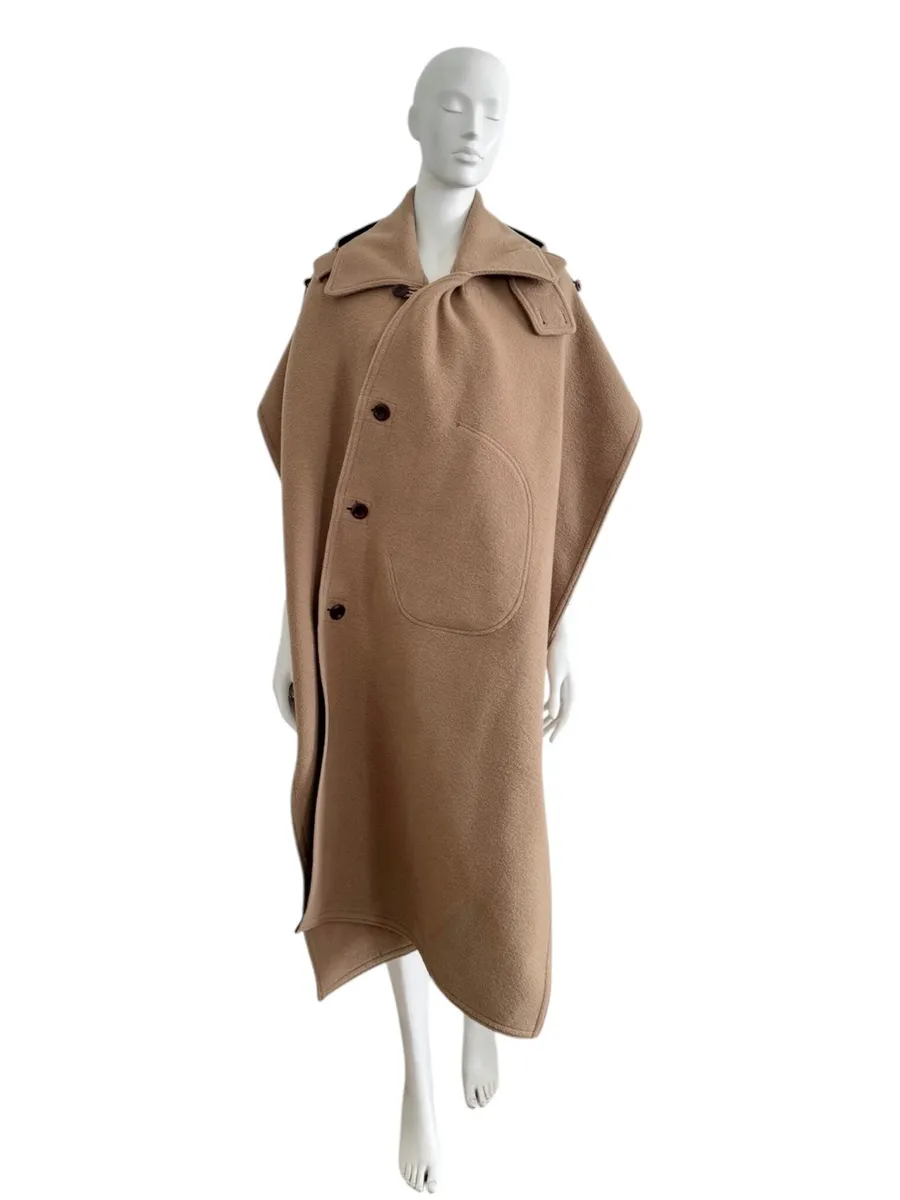 Cape en laine beige camel Junya Watanabe pour Comme des Garçons Homme, collection automne-hiver 2016.
Coupe ample et asymétrique, fermeture boutonnée devant, capuche intégrée et dos ouvert. Doublure noire contrastante, structure drapée.
Taille unique. État : 10/10. 3