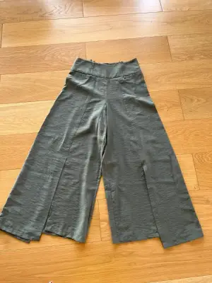 Pantalon taille haute, fendu sur l’avant et asymétrique cop.copine. Excellent état, Taille 38. Arrive à mi mollet.