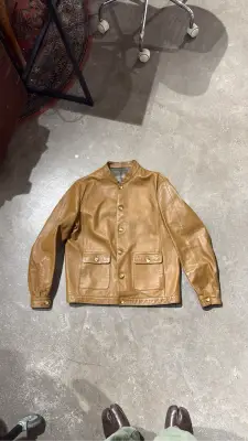 Veste en cuir camel à col montant, style vintage, avec fermeture boutonnée et poches plaquées, pour homme.