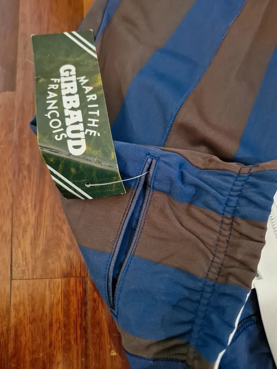 Bermuda Marithè & Francois Girbaud taille 44. Neufs avec étiquette. Fabriqués en Italie à la fin des années 80 dans un tissu polyester fin et particulier, typique de la maison. Ils présentent une ligne souple sur la cuisse qui se resserre vers le bas. Créativité stylistique et savoir-faire en matière de design fusionnent dans cette pièce iconique qui transcende le temps. Comme le montrent les photos, les bermudas sont NEUFS avec un sceau plastifié sur l'étiquette, ce qui en fait une véritable rareté. Destinés aux collectionneurs, aux amateurs de la marque et à quiconque désire une pièce au charme vintage et au goût contemporain.
Taille très petit.
Ceinture élastiquée.
Poches arrière passepoilées.
Tissu 100% polyester.
Fabriqué en Italie. 5