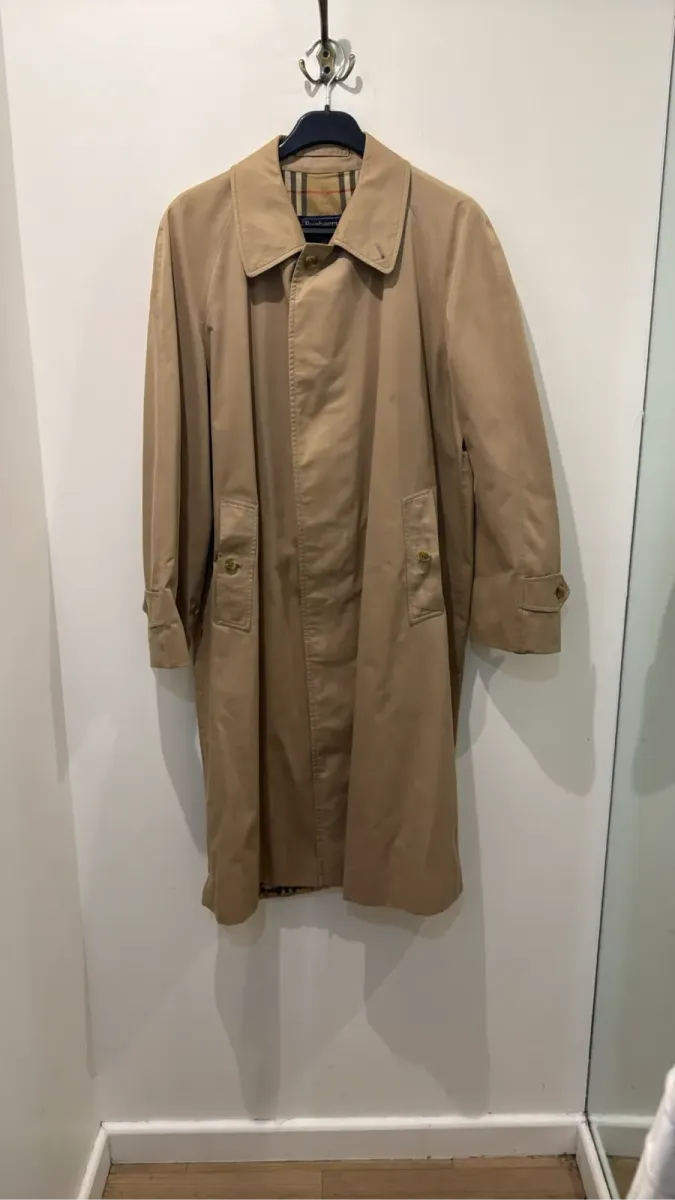 Trench-coat classique Burberrys' de couleur camel avec doublure à motif écossais, présentant quelques taches visibles sur le devant.