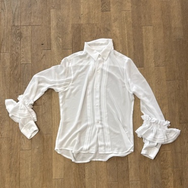 Blouse blanche transparente H&M x Comme des Garçons avec détails de plis nervurés sur le devant et poignets à volants.