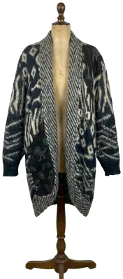 Cardigan long en maille duveteuse à motifs géométriques gris et écru, avec des empiècements décoratifs sombres, typique des années 80. Mohair
